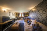 Luxurious chalet living room with plush sofas, a large flat-screen TV, and a rustic wooden coffee table.