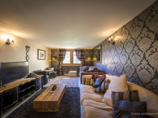 Luxurious chalet living room with plush sofas, a large flat-screen TV, and a rustic wooden coffee table.