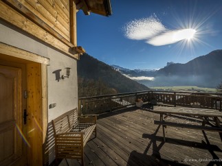 Mountain view chalet with wooden deck and bench.
