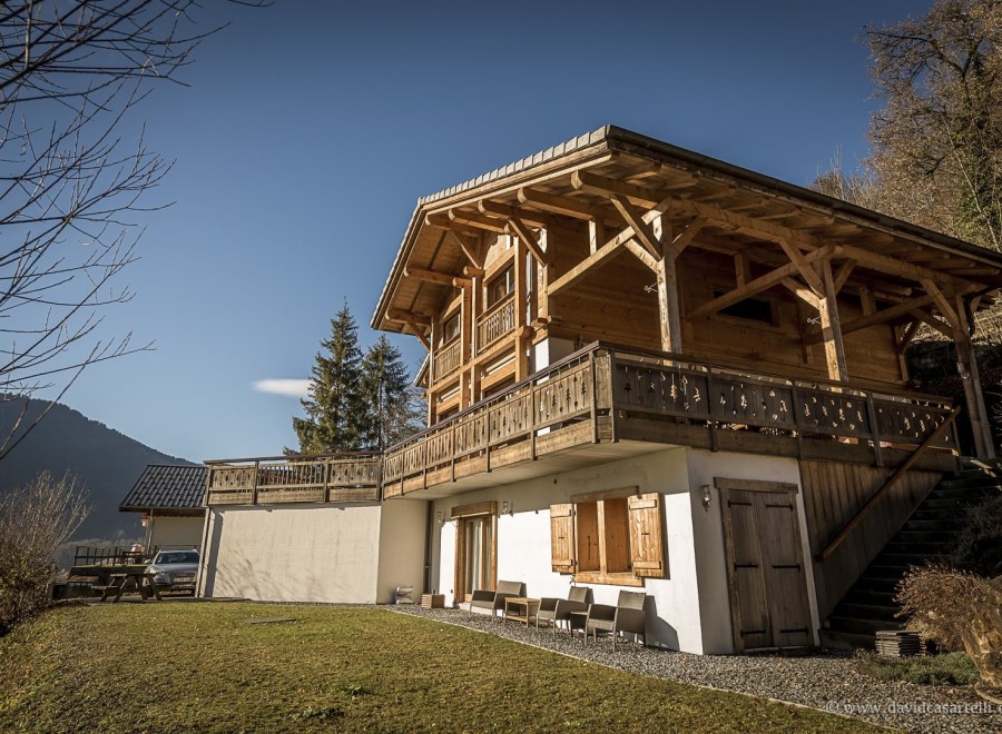This stunning chalet boasts a spacious wooden exterior, expansive balconies offering breathtaking mountain views, and a charming lower level with rustic details.