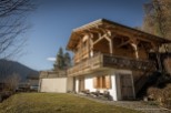 This stunning chalet boasts a spacious wooden exterior, expansive balconies offering breathtaking mountain views, and a charming lower level with rustic details.