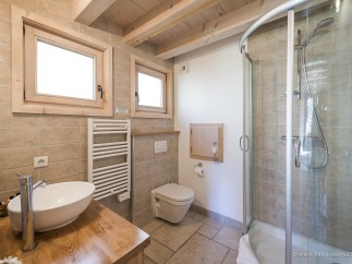 This stunning bathroom boasts a spacious shower enclosure, modern sink and toilet, and heated towel rack.