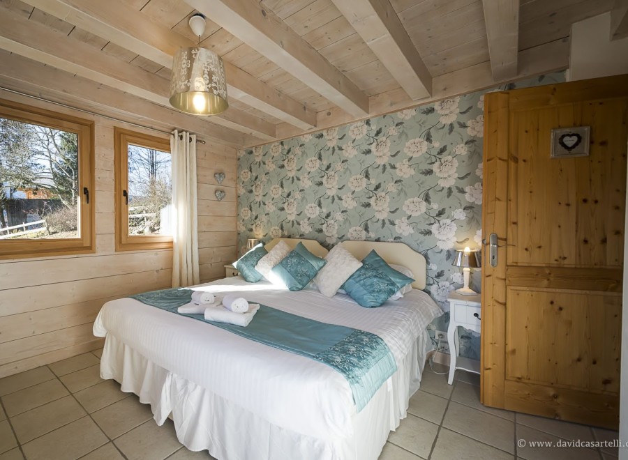 Charming bedroom with floral wallpaper and wooden beams.