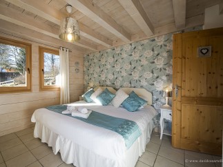 Charming bedroom with floral wallpaper and wooden beams.