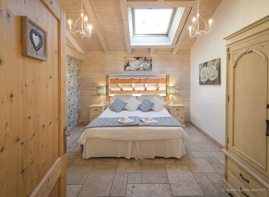 Charming bedroom with wooden beams, skylights, and a cozy atmosphere.
