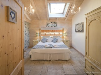 Charming bedroom with wooden beams, skylights, and a cozy atmosphere.