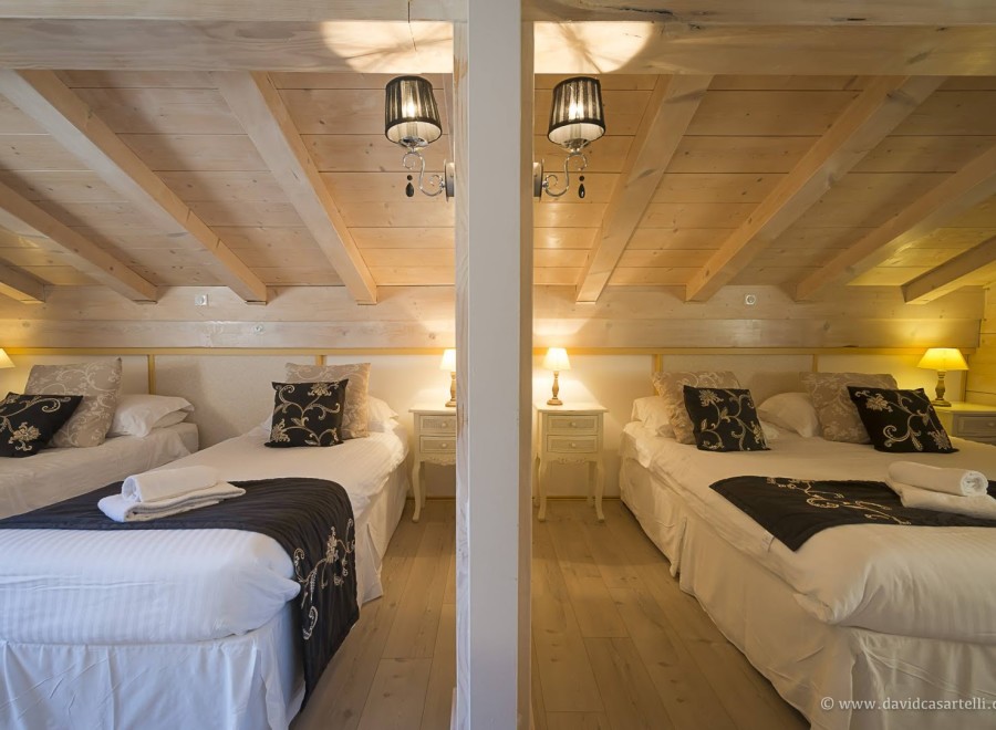 Cozy chalet bedrooms with twin beds, featuring elegant bedding and warm lighting.