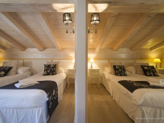 Cozy chalet bedrooms with twin beds, featuring elegant bedding and warm lighting.