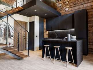 Discover modern living in this stunning property, featuring a sleek kitchen with black cabinetry and a stylish breakfast bar.