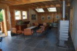 Cozy chalet living room with wood-beamed ceiling, large windows, and a wood-burning stove.
