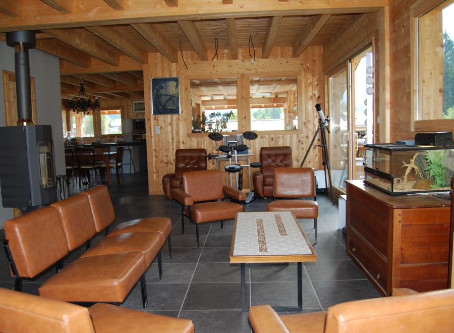 This stunning chalet boasts a spacious open-plan living area with exposed wooden beams and a cozy wood-burning stove.