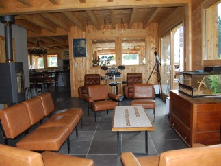 This stunning chalet boasts a spacious open-plan living area with exposed wooden beams and a cozy wood-burning stove.