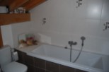 This charming bathroom boasts a modern bathtub with a shower attachment, complemented by stylish dark brown tiles.