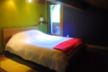 Cozy bedroom with a double bed, featuring a light-colored duvet and a red blanket.