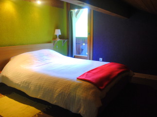 Cozy bedroom with a double bed, featuring a light-colored duvet and a red blanket.