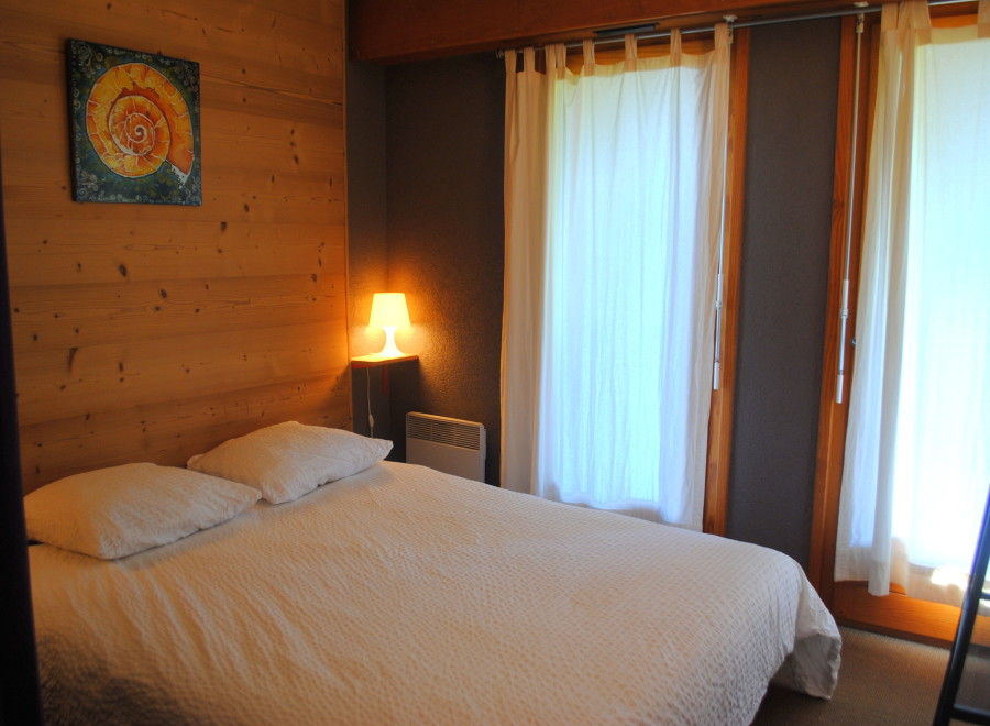 Cozy bedroom with wooden walls and white bedding.