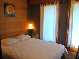 Cozy bedroom with wooden walls and white bedding.