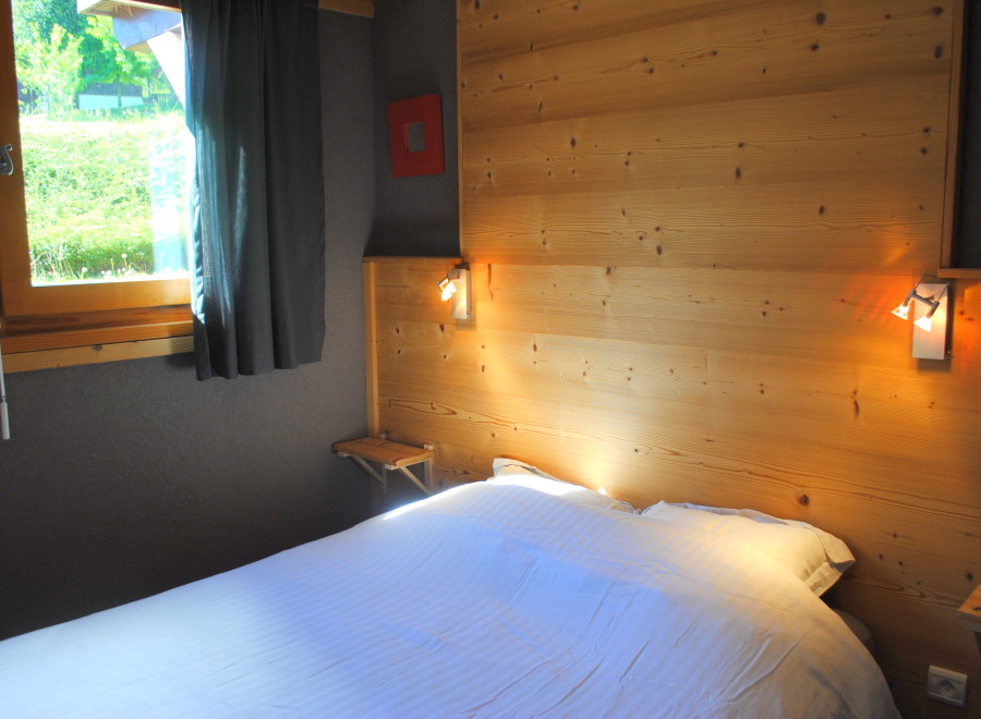 Cozy bedroom with wooden walls and a comfortable bed.