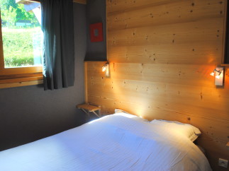 Cozy bedroom with wooden walls and a comfortable bed.