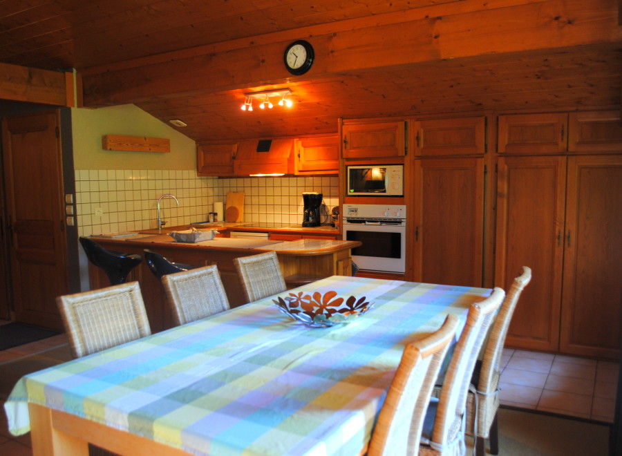 Cozy chalet kitchen with wooden cabinets and a dining area featuring a checkered tablecloth.