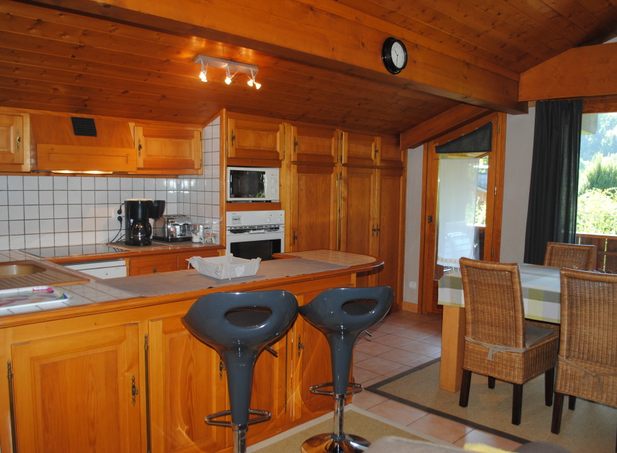 This charming chalet boasts a fully equipped kitchen with wooden cabinetry, modern appliances, and a breakfast bar with bar stools.