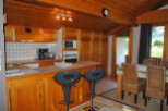 This charming chalet boasts a fully equipped kitchen with wooden cabinetry, modern appliances, and a breakfast bar with bar stools.