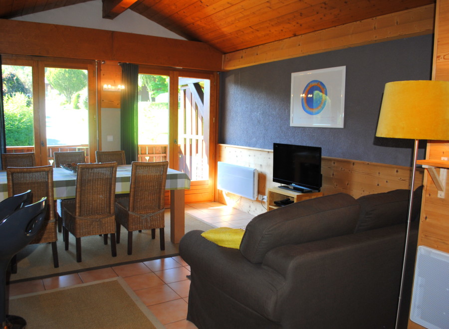 This charming chalet boasts a spacious living area with a comfortable sofa and flat-screen TV, perfect for relaxing after a day of outdoor activities.