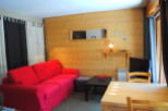 Cozy living room with red couch and wood wall.