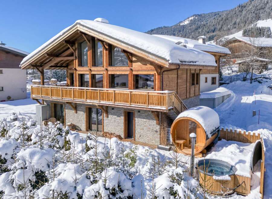 This stunning chalet boasts a beautiful wooden design and is nestled in a snowy mountain landscape.