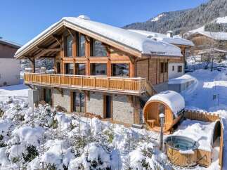 This stunning chalet boasts a beautiful wooden design and is nestled in a snowy mountain landscape.