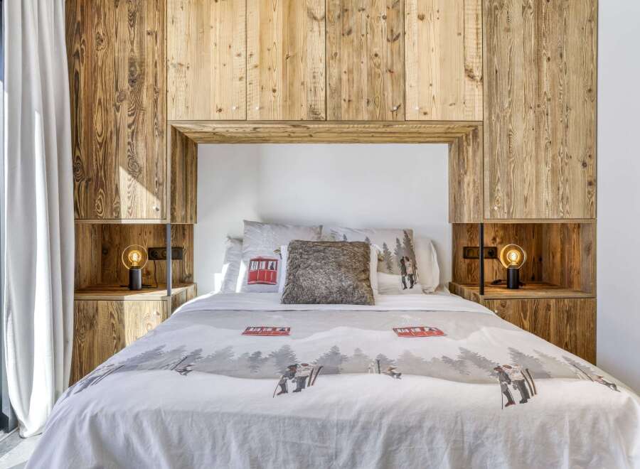 This cozy bedroom features a stunning wooden headboard and built-in shelving, creating a warm and inviting atmosphere.