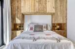 This cozy bedroom features a stunning wooden headboard and built-in shelving, creating a warm and inviting atmosphere.