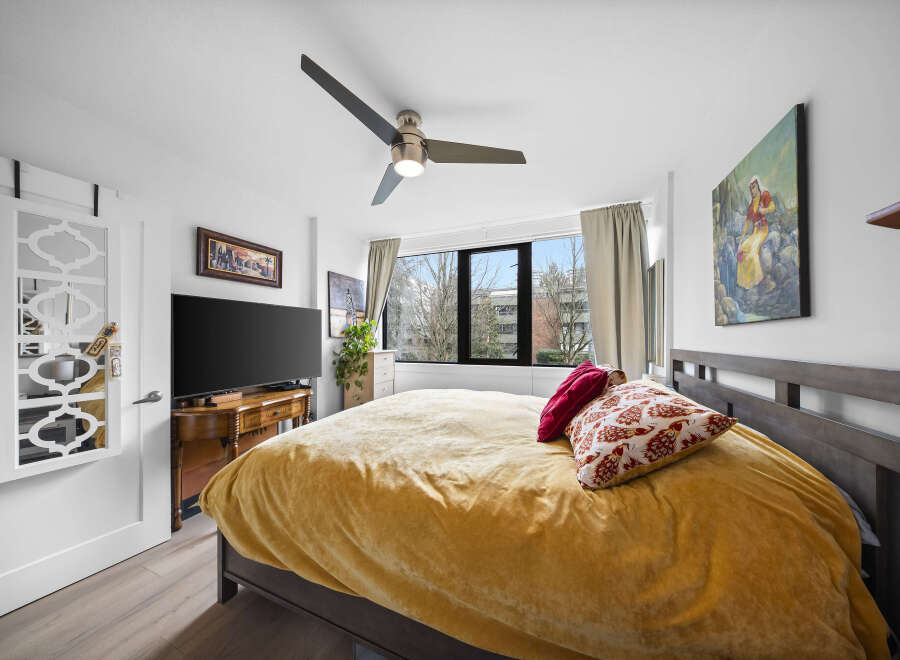 Step into this inviting bedroom, featuring a cozy bed adorned with plush pillows and a vibrant yellow comforter.