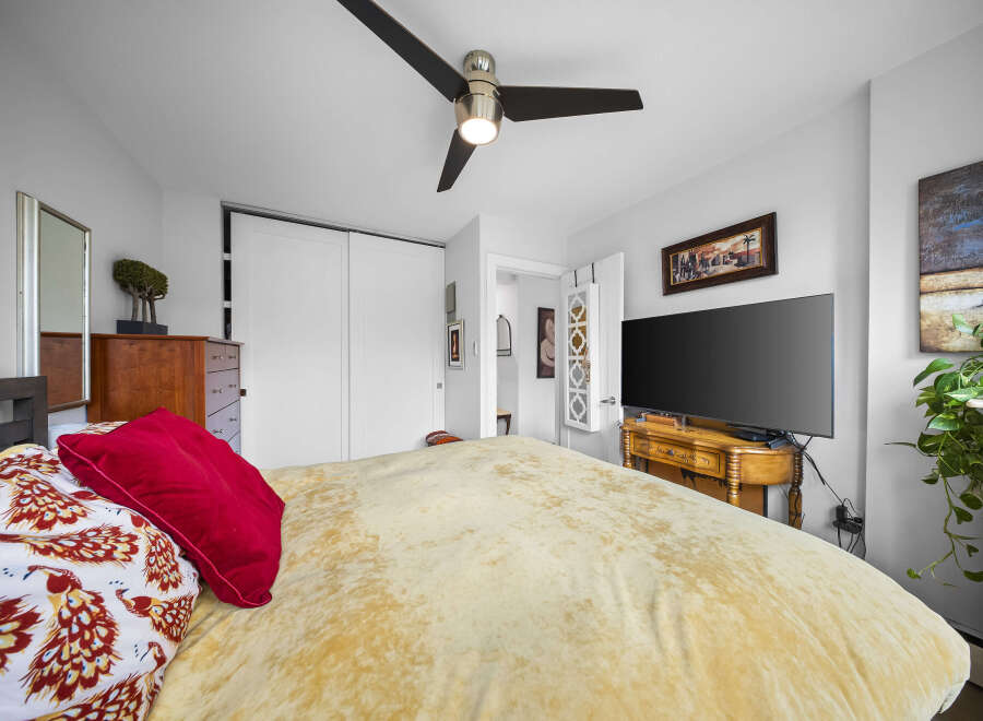 Step into this inviting bedroom, featuring a comfortable bed with a stylish red pillow and patterned bedding.