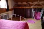 Charming attic bedroom with a comfy pink bed and a hanging chair, perfect for relaxing.