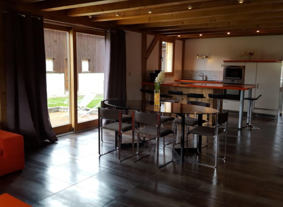 This stunning chalet boasts an open-plan living area with a sleek, modern kitchen and a large dining table perfect for entertaining.