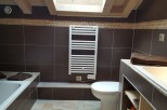 This stunning bathroom boasts a modern design with dark brown tiles and a built-in bathtub.