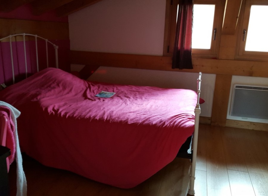 Cozy attic bedroom with a comfortable double bed and bright windows.