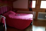 Cozy attic bedroom with a comfortable double bed and bright windows.