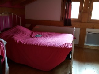 Cozy attic bedroom with a comfortable double bed and bright windows.