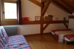 Cozy attic bedroom with wooden beams, featuring a comfortable sofa bed and a single bed, perfect for a relaxing getaway.