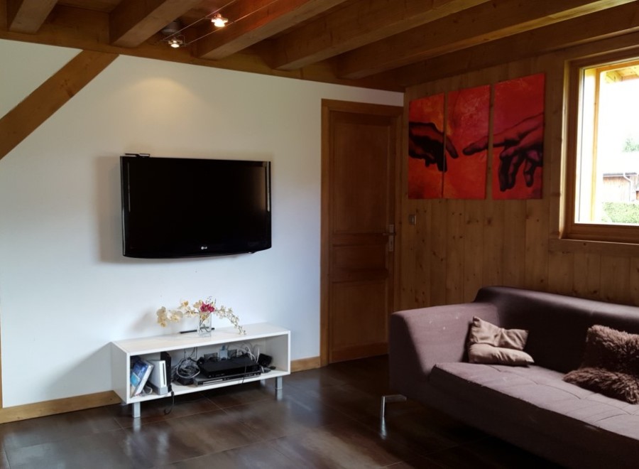 Cozy chalet living room with exposed wooden beams, a flat-screen TV, and a comfortable couch.