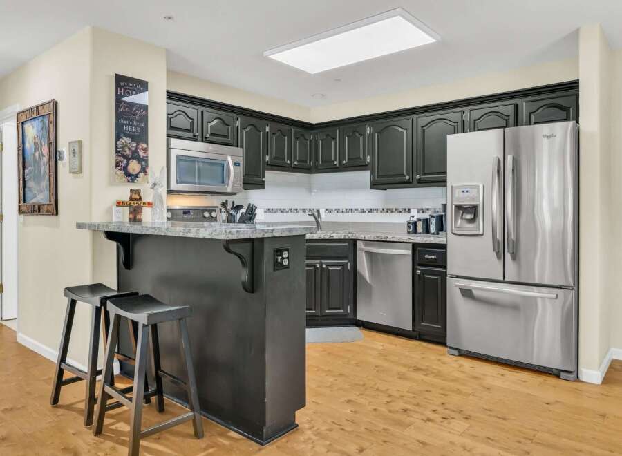 This stunning kitchen boasts modern appliances and sleek black cabinetry, perfect for any home chef.