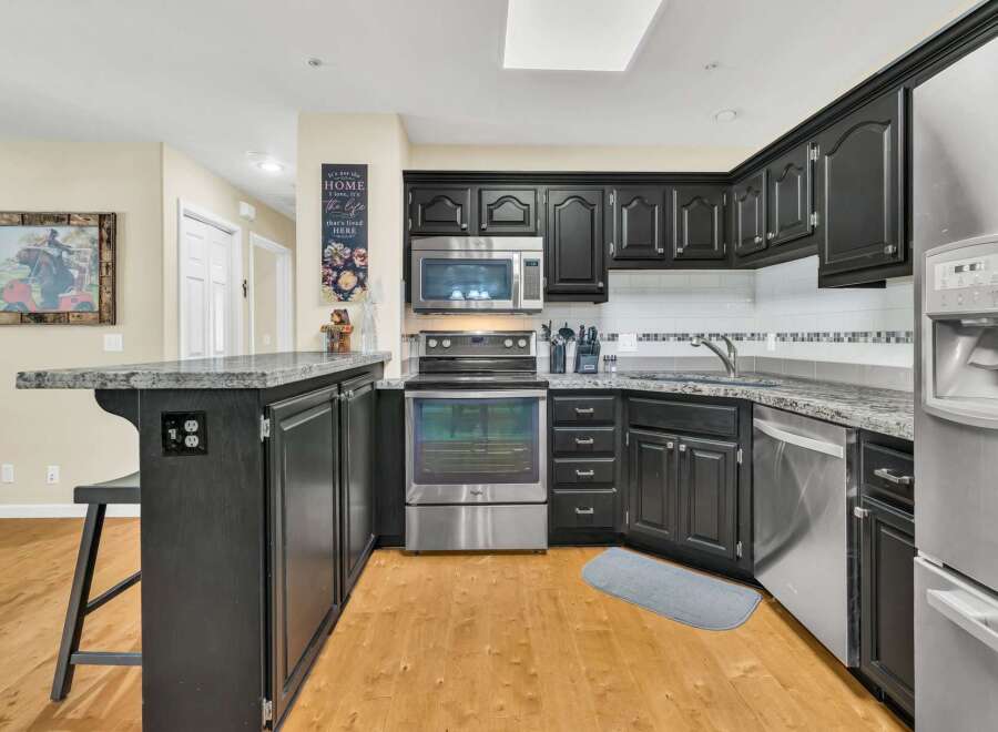 This stunning kitchen boasts modern appliances and sleek black cabinetry, perfect for culinary enthusiasts.