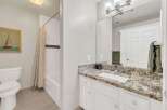 This beautiful bathroom features a modern design with a granite countertop and white cabinetry.