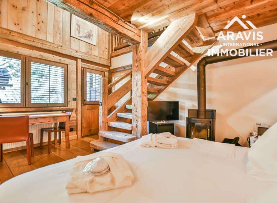 Experience the charm of this stunning wooden chalet, featuring a cozy bedroom with a fireplace and a unique wooden staircase.