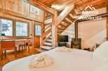 Experience the charm of this stunning wooden chalet, featuring a cozy bedroom with a fireplace and a unique wooden staircase.