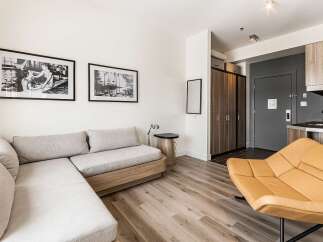 Discover modern living in this stylish apartment! Featuring a comfortable sectional sofa, a unique accent chair, and sleek hardwood floors, this space is perfect for relaxation and entertaining.