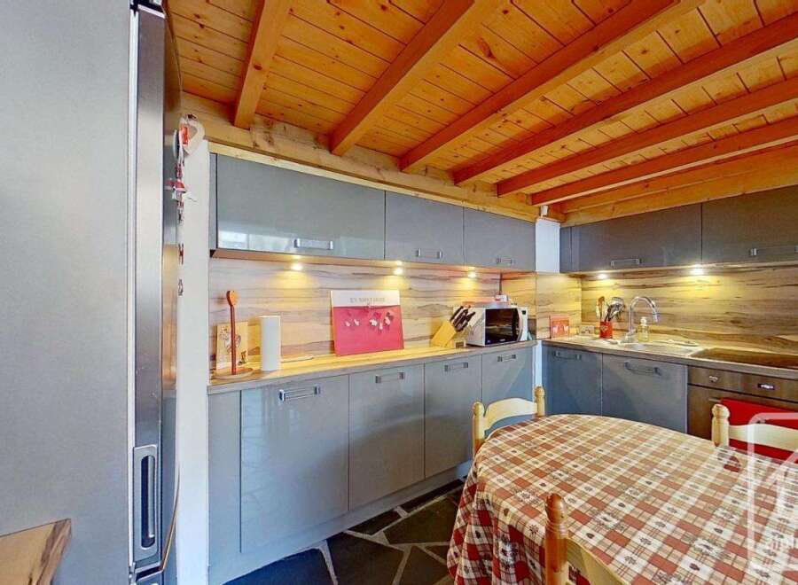 This charming kitchen boasts a rustic wooden ceiling and modern gray cabinetry, creating a perfect blend of style and functionality.