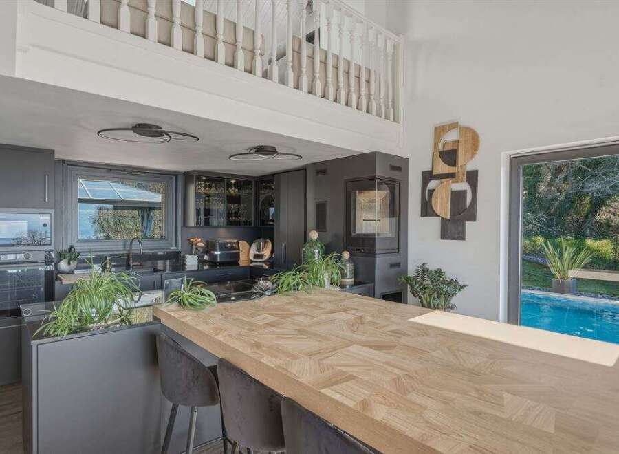 This stunning kitchen boasts a modern design with sleek, dark cabinetry and a spacious wooden island, perfect for both cooking and entertaining.